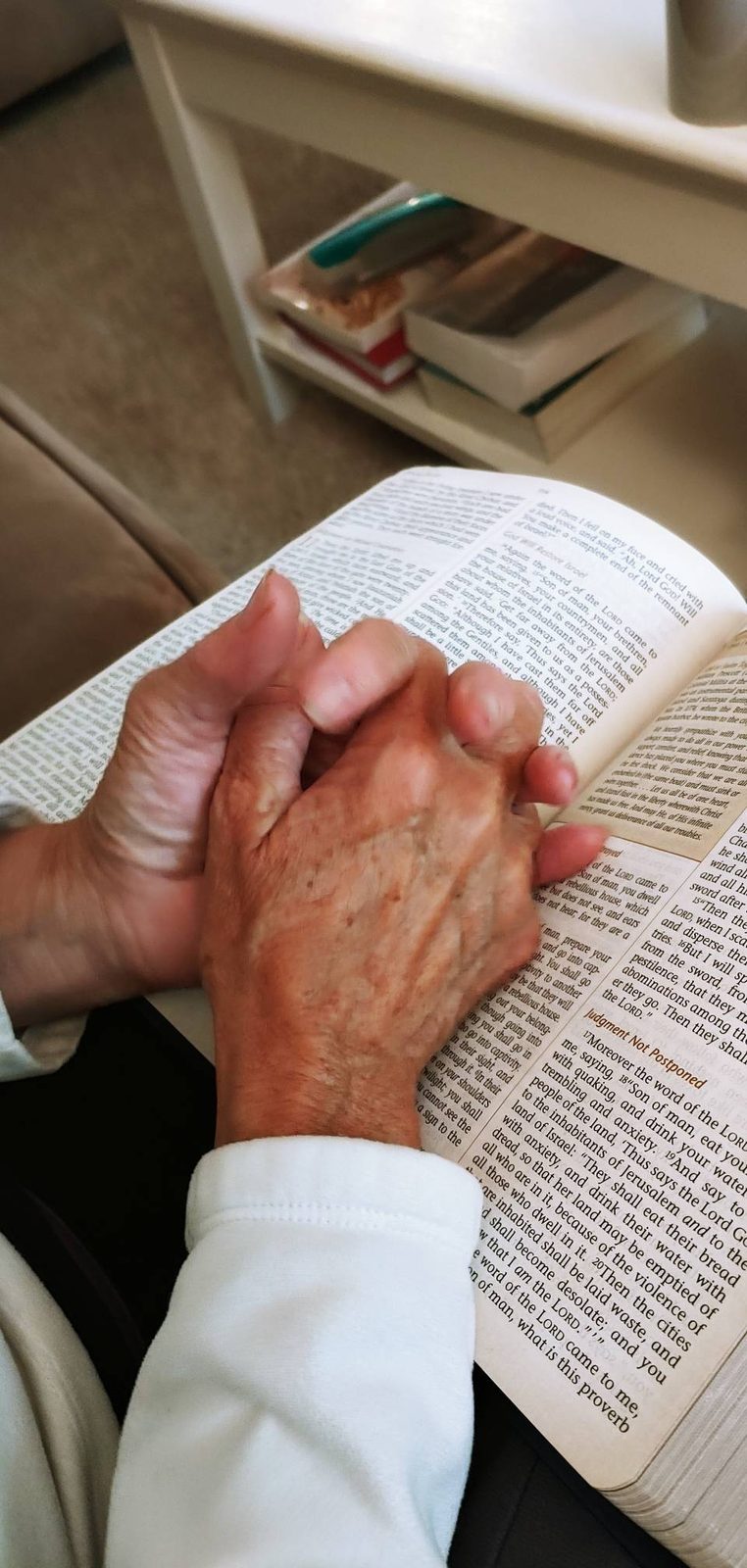 Hands folded in prayer over an open Bible